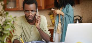 A photo showing a man on the telephone in a kitchen, with a woman standing behind him
