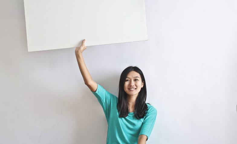 Stock photo of smiling woman holding up a blank poster