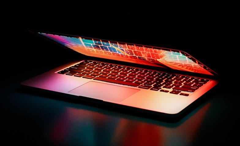 A stock photo of a laptop computer half-opened in low light