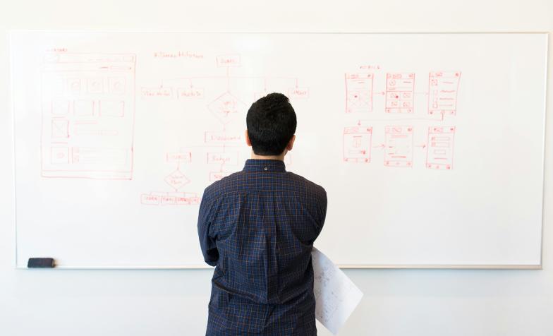 A stock photo showing someone looking at a whiteboard full of data