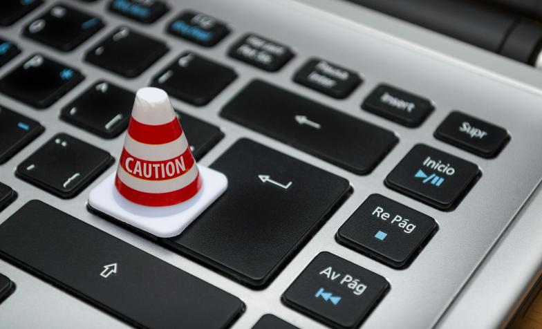 A stock photo of a traffic cone perched on a computer keyboard