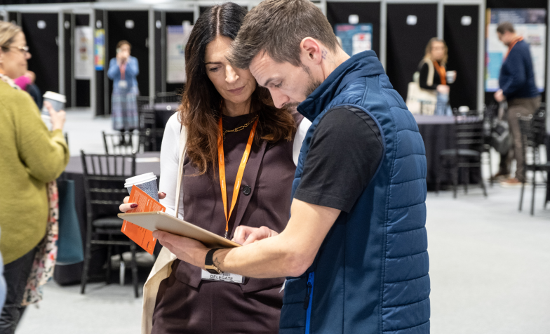 Two people looking at a leaflet together at the exhibition at National Conference 2024