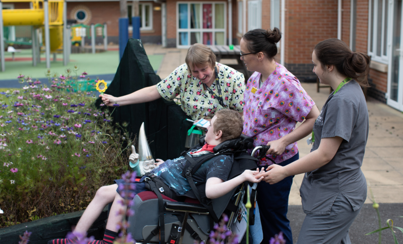 A group of people caring for a young person in a wheelchair in a hospice garden