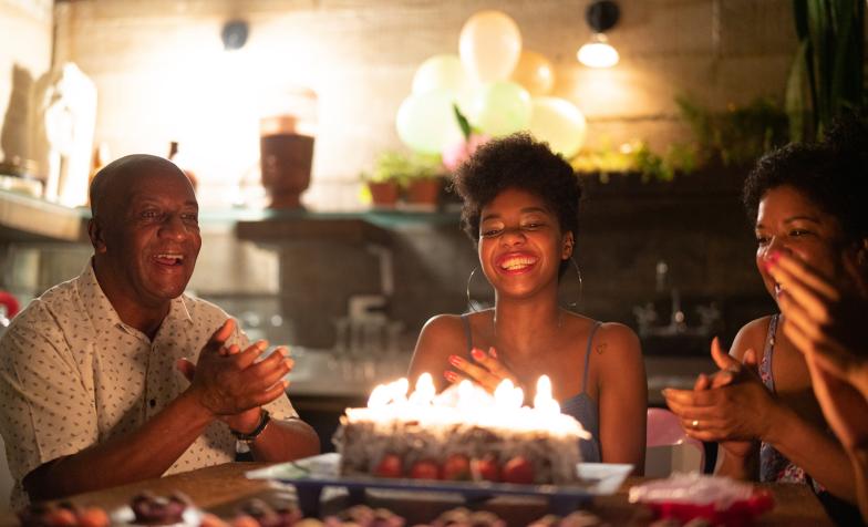 Three people gathered around a birthday cake