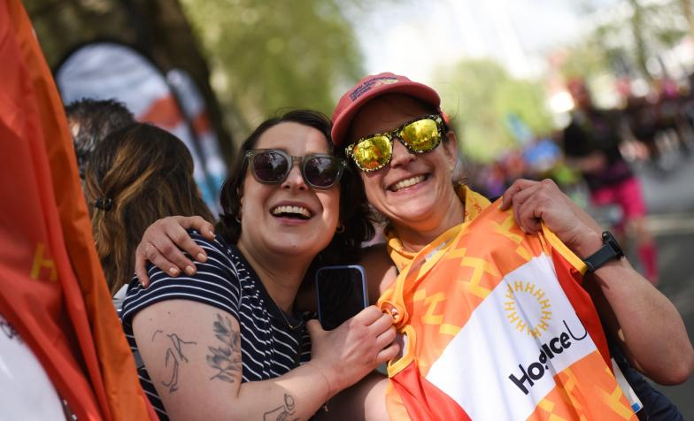 Two people hugging, with one holding up a Hospice UK running vest 