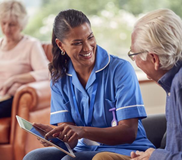 Hospice UK and Corndel launch Hospice Data Academy - image of nurse showing information to patient on and iPad