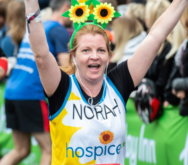 Female runner in Hospice UK top wearing sunflower boppers on head