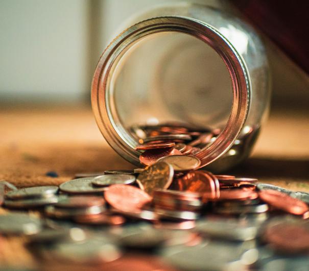 A stock photograph from Unsplash showng a jar tipped over, that had been filled with money