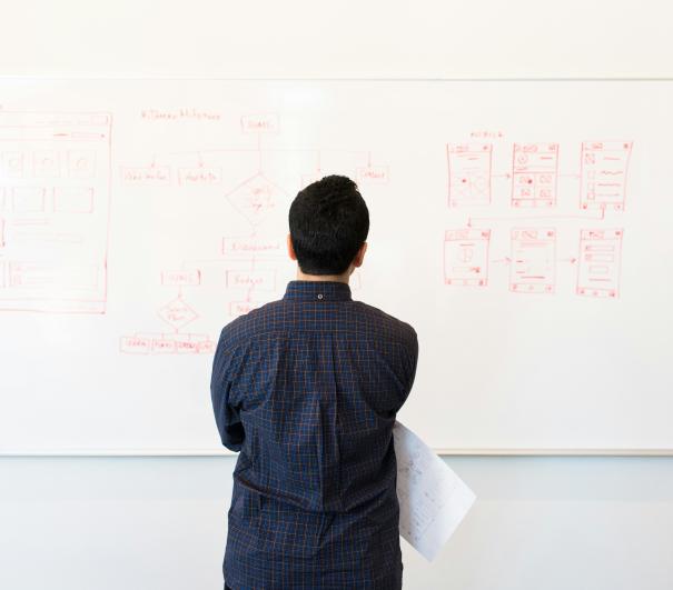 A stock photo showing someone looking at a whiteboard full of data