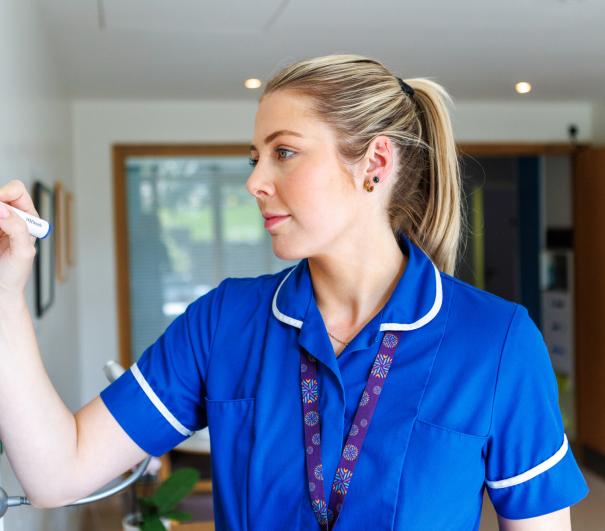 A nurse at Royal Trinity Hospice completing a whiteboard of information