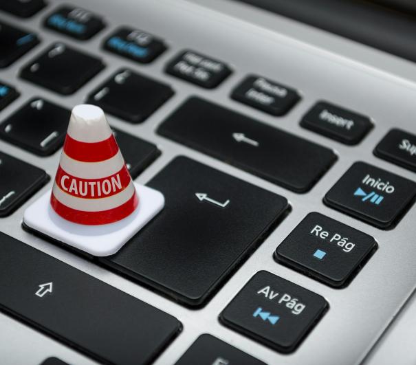 A stock photo of a traffic cone perched on a computer keyboard