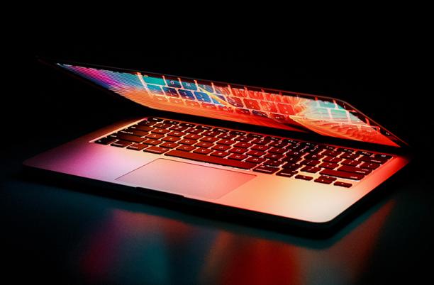 A stock photo of a laptop computer half-opened in low light