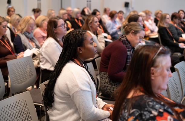 An audience of people seated at a conference session.