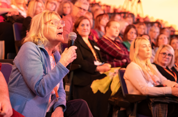 A woman in the audience at National Conference asking a question into a microphone