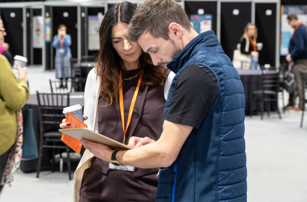 Two people looking at a leaflet together at the exhibition at National Conference 2024