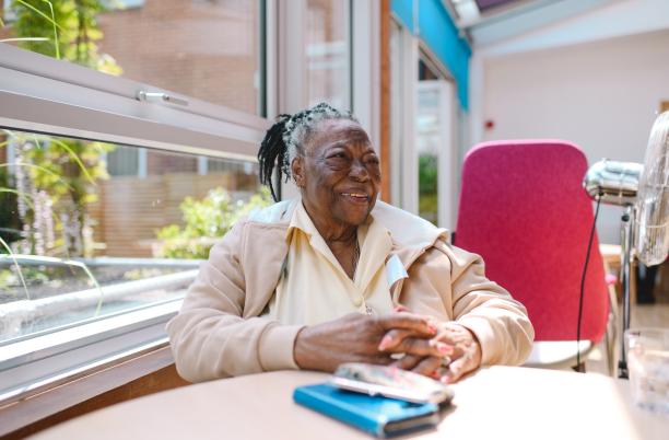 Patient in a hospice sat at a table and smiling