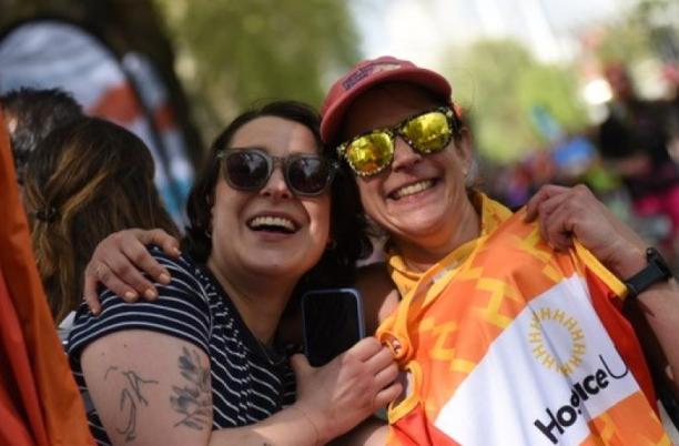 Two people hugging, with one holding up a Hospice UK running vest 