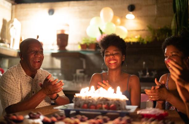Three people gathered around a birthday cake