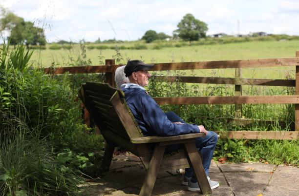 A couple sitting on a bench looking out to a field