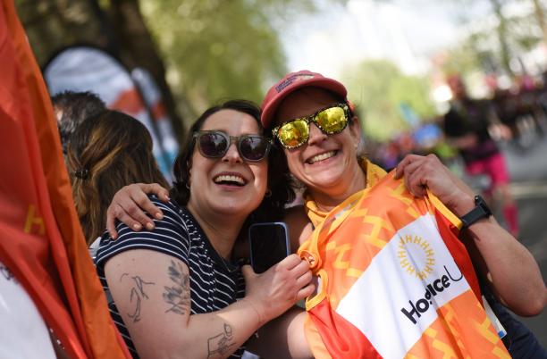 Two people hugging, with one holding up a Hospice UK running vest 