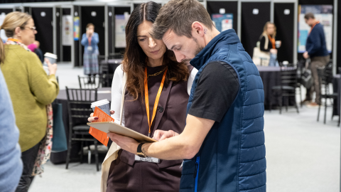 Two people looking at a leaflet together at the exhibition at National Conference 2024