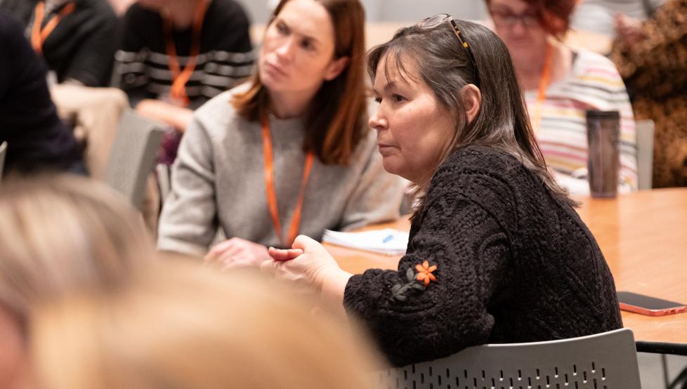 Two women seated at a table taking part in a conference session