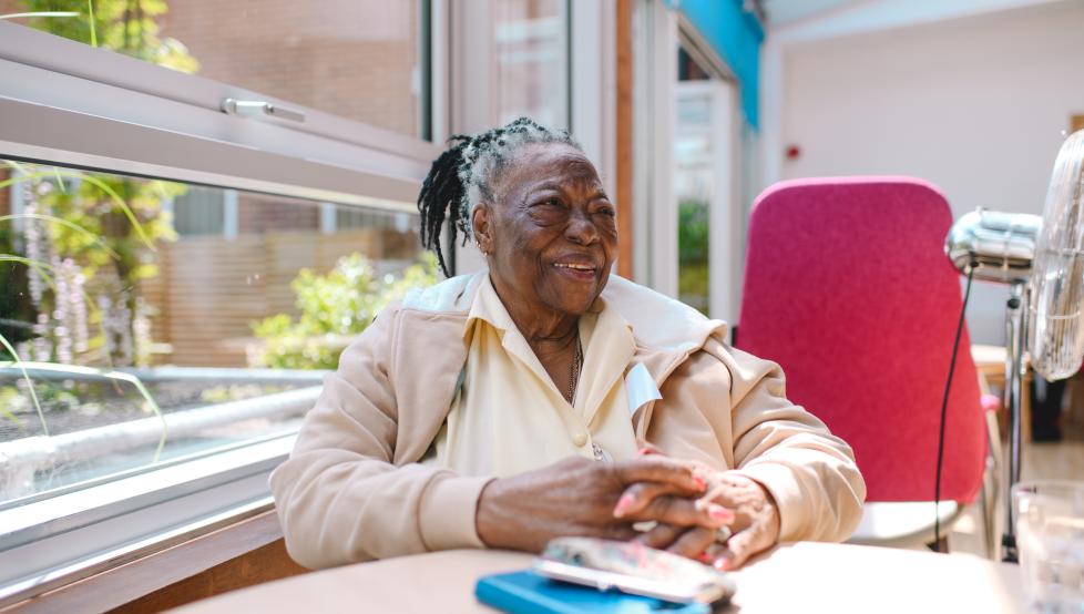 Patient in a hospice sat at a table and smiling