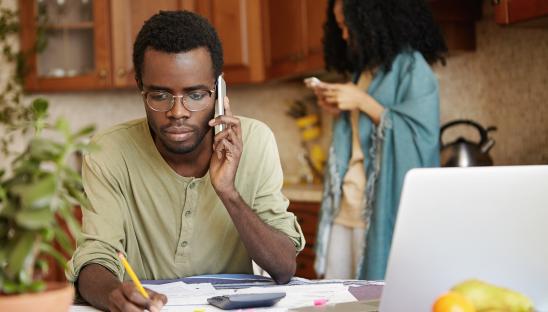 A photo showing a man on the telephone in a kitchen, with a woman standing behind him
