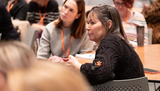 Two women seated at a table taking part in a conference session
