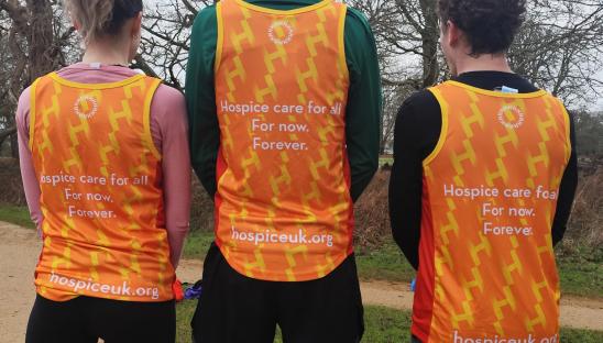 three runners in the park wearing Hospice UK running vests